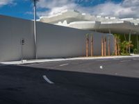 a car drives past an industrial looking white building with palm trees in the foreground