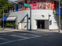 there is a large white building that is at an intersection and there are a few green street signs at the corner