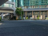 an empty road with a street sign at the curb in front of an office building