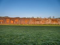 this grass field has been cut short to cover the area in the distance, and it is a grassy area next to an old building