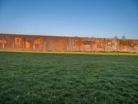 this grass field has been cut short to cover the area in the distance, and it is a grassy area next to an old building