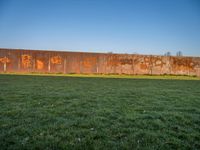 this grass field has been cut short to cover the area in the distance, and it is a grassy area next to an old building