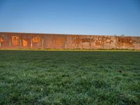 this grass field has been cut short to cover the area in the distance, and it is a grassy area next to an old building