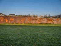 this grass field has been cut short to cover the area in the distance, and it is a grassy area next to an old building