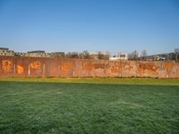 this grass field has been cut short to cover the area in the distance, and it is a grassy area next to an old building