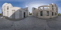 a couple of buildings with a person walking in front of them walking through a courtyard