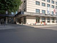 an office building with people walking up and down the street from it on a sidewalk