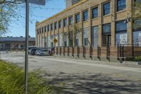 an empty street with cars parked near the curb in front of a building on a sunny day