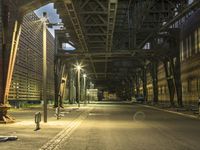 empty street in urban setting with parking meters and an industrial bridge, in the background