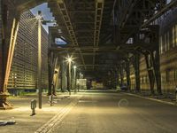 empty street in urban setting with parking meters and an industrial bridge, in the background