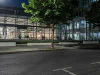 an empty parking lot in the middle of an urban neighborhood at night with people walking on the sidewalk and cars driving