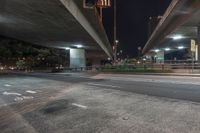 an elevated freeway bridge in night time with a person walking by it and the light from the street lamps shine on