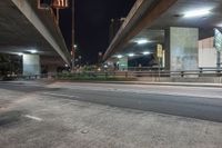 an elevated freeway bridge in night time with a person walking by it and the light from the street lamps shine on