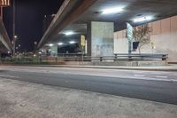 an elevated freeway bridge in night time with a person walking by it and the light from the street lamps shine on