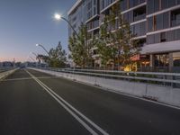 a road with no traffic on it at night next to a tall building in the background