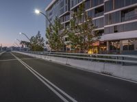 a road with no traffic on it at night next to a tall building in the background