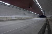 empty highway inside a concrete tunnel with metal railings and ceiling covering it in light gray