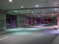 a view of a parking garage at night with a person standing on a red fire hydrant