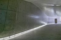 a man standing in a building looking down at an indoor tunnel underneath a bridge that is built to allow people walking on the ground