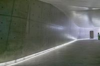 a man standing in a building looking down at an indoor tunnel underneath a bridge that is built to allow people walking on the ground