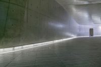 a man standing in a building looking down at an indoor tunnel underneath a bridge that is built to allow people walking on the ground