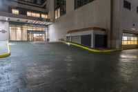 there is an empty parking garage on the street outside the building at night time with bright lights