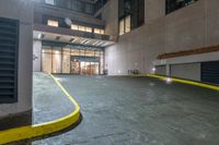 there is an empty parking garage on the street outside the building at night time with bright lights