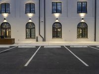 two parking lots with one street light on each side of the building and a concrete parking lot next to it