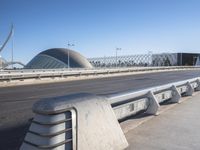 a close shot of a bench near the road by a bridge at an airport with buildings