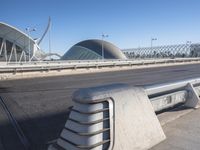 a close shot of a bench near the road by a bridge at an airport with buildings