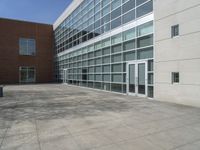 a brick walkway outside a building with glass doors and a large window sill on the ground