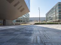 a tiled surface on the street of an office building with tall windows and a lot of space