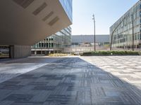 a tiled surface on the street of an office building with tall windows and a lot of space