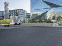 the large glass building has a long line of buildings in the middle of it and a man is riding a bike