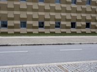 a man on a skateboard is riding next to the building and grass outside it