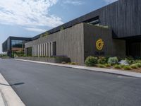 a building with a logo painted on the side near a street that has a sidewalk next to it