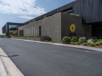 a building with a logo painted on the side near a street that has a sidewalk next to it