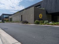 a building with a logo painted on the side near a street that has a sidewalk next to it