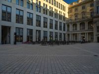 a courtyard with a building on the other side and a large white building with many windows