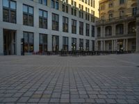 a courtyard with a building on the other side and a large white building with many windows