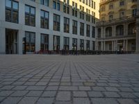 a courtyard with a building on the other side and a large white building with many windows