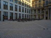 a courtyard with a building on the other side and a large white building with many windows