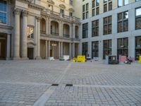 a courtyard with a building on the other side and a large white building with many windows