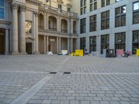 a courtyard with a building on the other side and a large white building with many windows