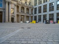 a courtyard with a building on the other side and a large white building with many windows