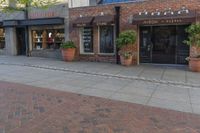 a restaurant sits on a brick side walk next to the street and sidewalk outside of it