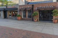 a restaurant sits on a brick side walk next to the street and sidewalk outside of it