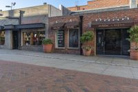 a restaurant sits on a brick side walk next to the street and sidewalk outside of it