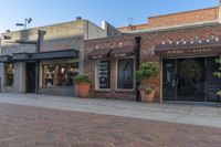 a restaurant sits on a brick side walk next to the street and sidewalk outside of it