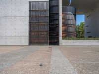 a modern building in the city with black shutters and a door open to an empty courtyard with trees on either side